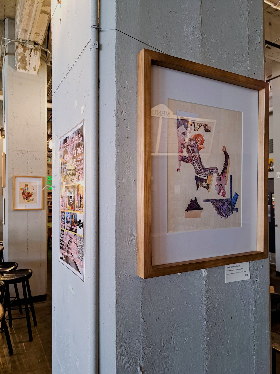 The collage on display, hung on a concrete pillar in a wooden frame.